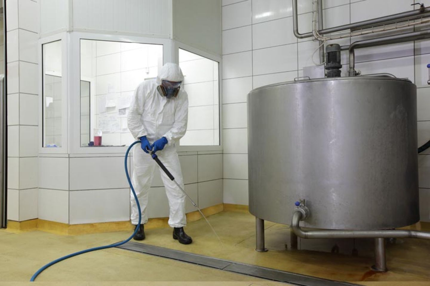 Man draagt beschermpak en gelaatsmasker tijdens schoonmaakwerkzaamheden