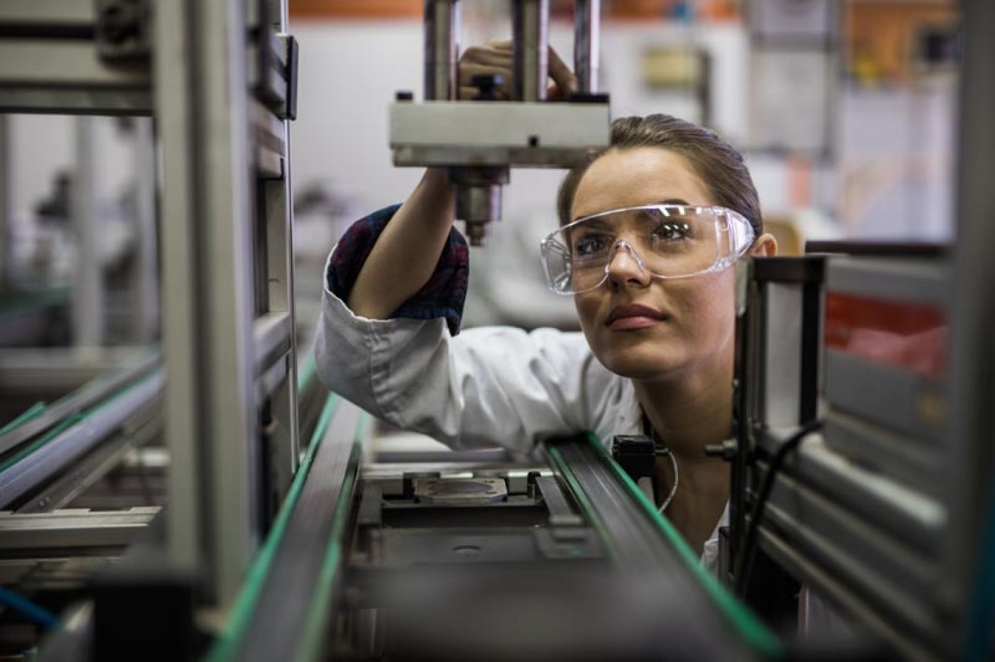 Vrouw bij productiemachine draagt veiligheidsbril