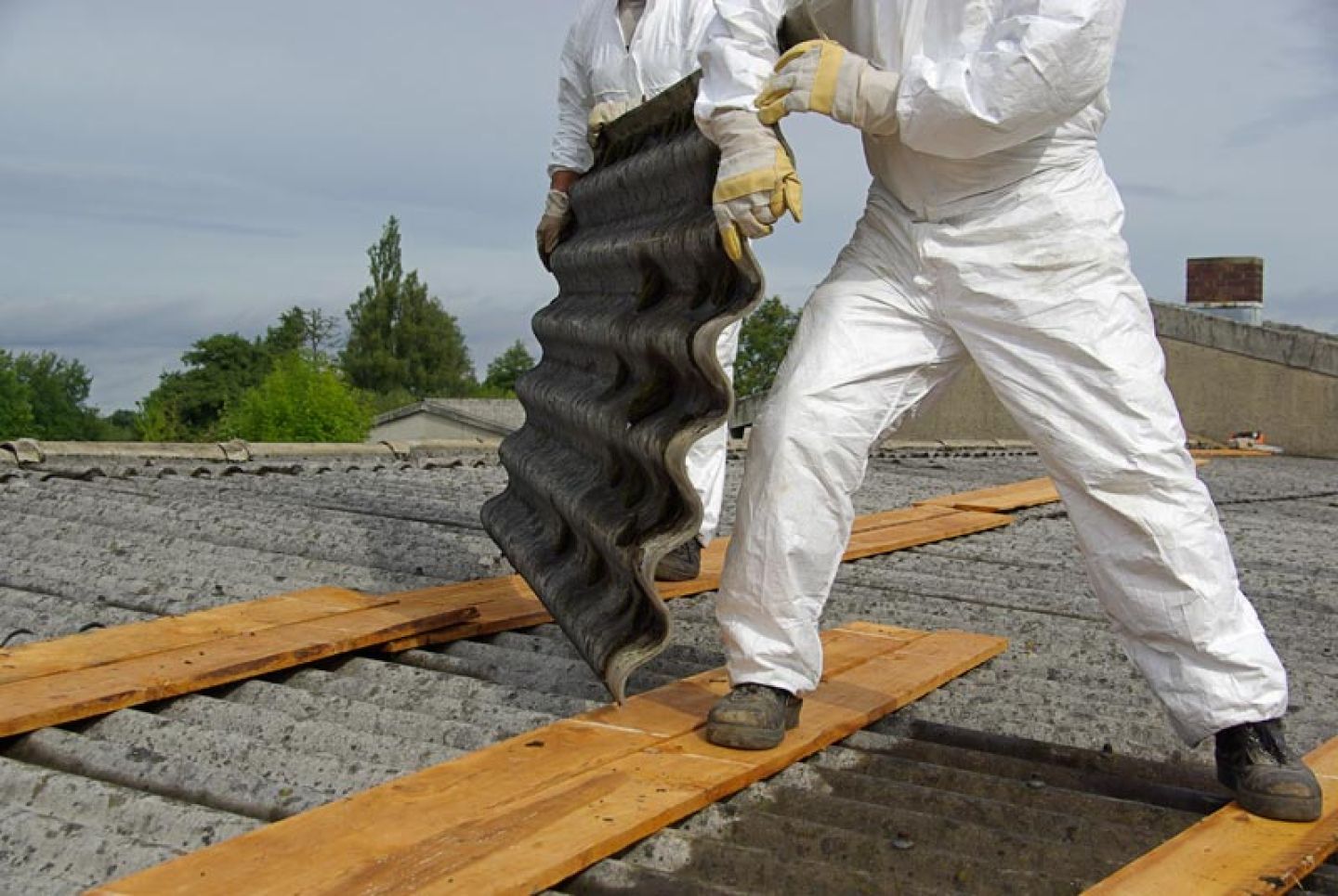 Twee werknemers dragen persoonlijke beschermingsmiddelen tijdens werkzaamheden met asbest