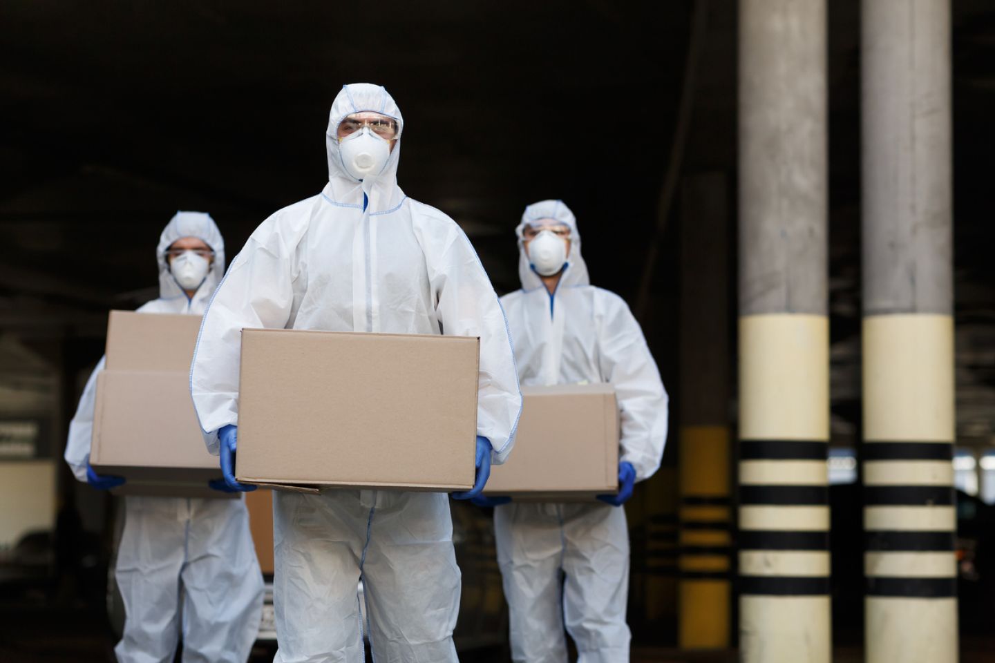 Drie mannen met FFP3 stofmaskers verplaatsen dozen met gevaarlijke stoffen
