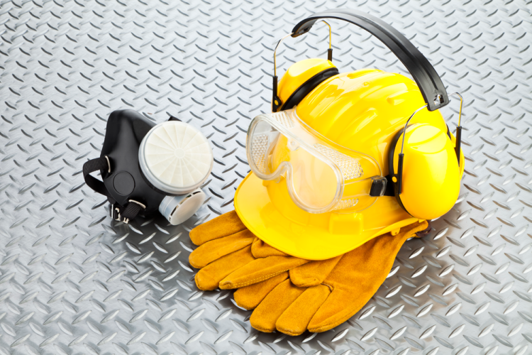 Zwart halfgelaatsmasker, heldere veiligheidsbril, gele helm, gele oorkappen en gele werkhandschoenen op een zilveren ondergrond