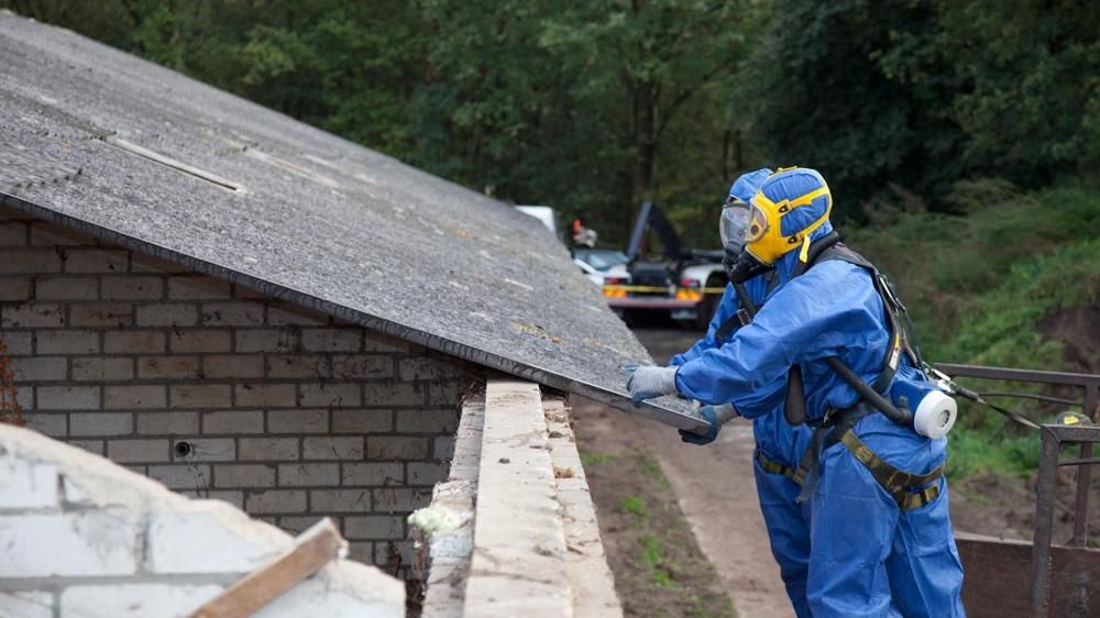 Twee mannen werken op een dak en zijn beschermd dankzij een overall en ademhalingssysteem