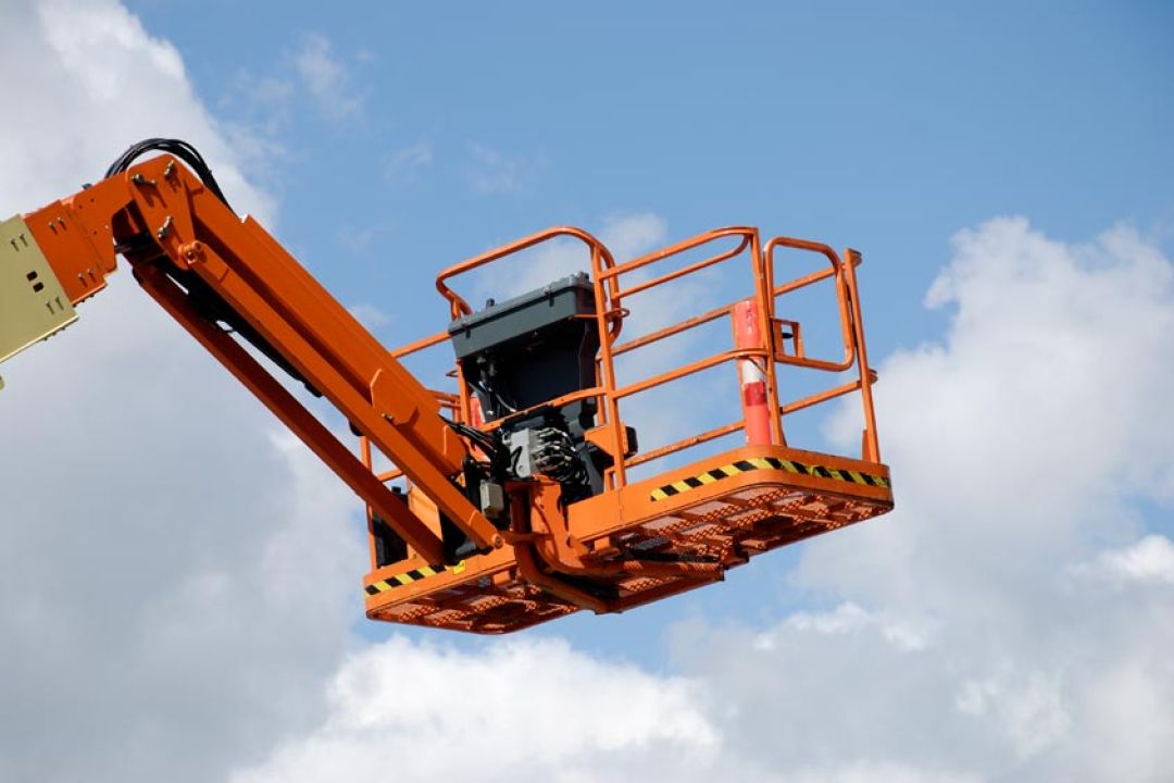 Oranje werkbak van hoogwerker met blauwe lucht als achtergrond