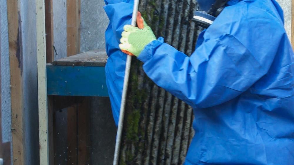 Man verwijdert asbest gehuld in persoonlijke beschermingsmiddelen