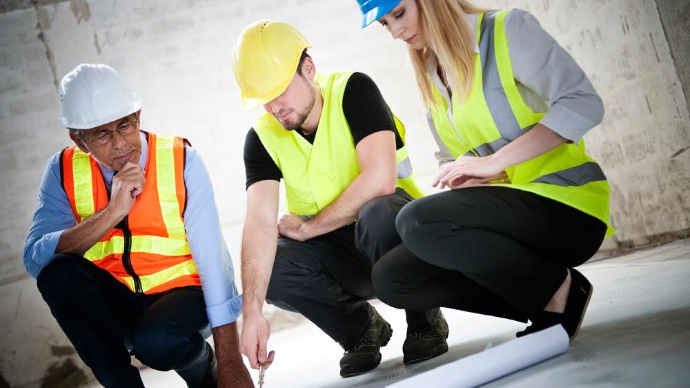 Een leidinggevende, medewerker en technische operator met een verschillende kleur veiligheidshelm op de bouwplaats