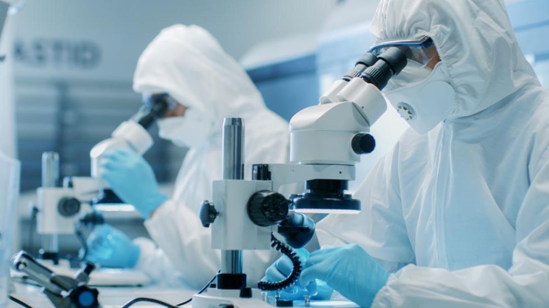 Twee mannen kijken door een microscoop en dragen AlphaTec chemische beschermingsmiddelen