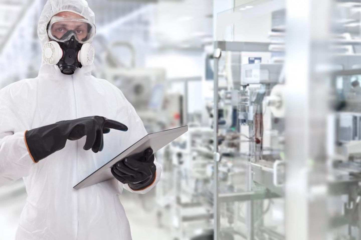 Man in lab met ipad draagt chemisch beschermpak