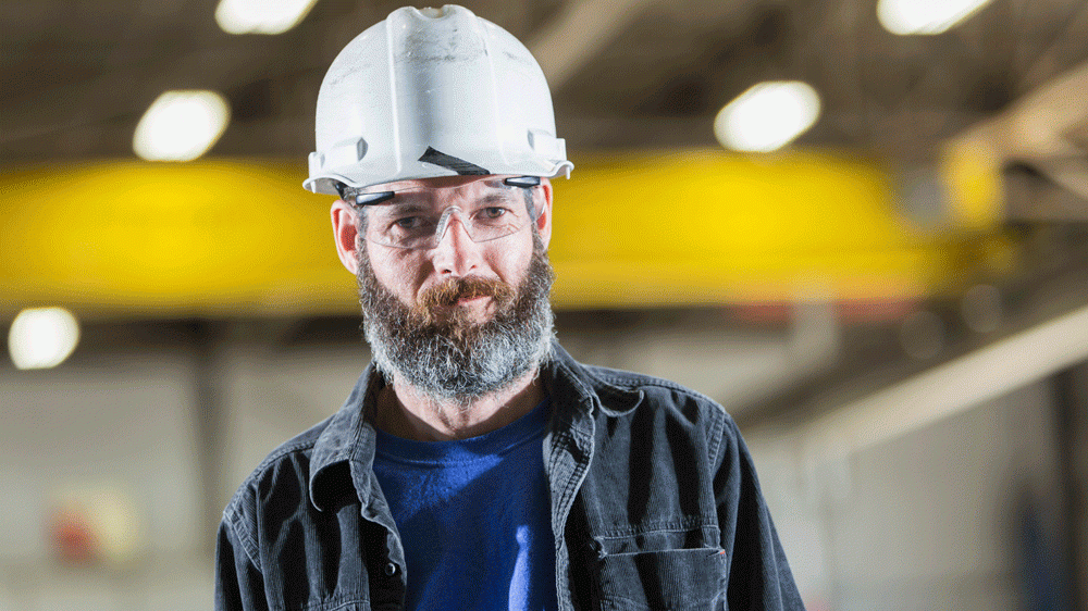 Man met baard draagt veiligheidsbril en helm